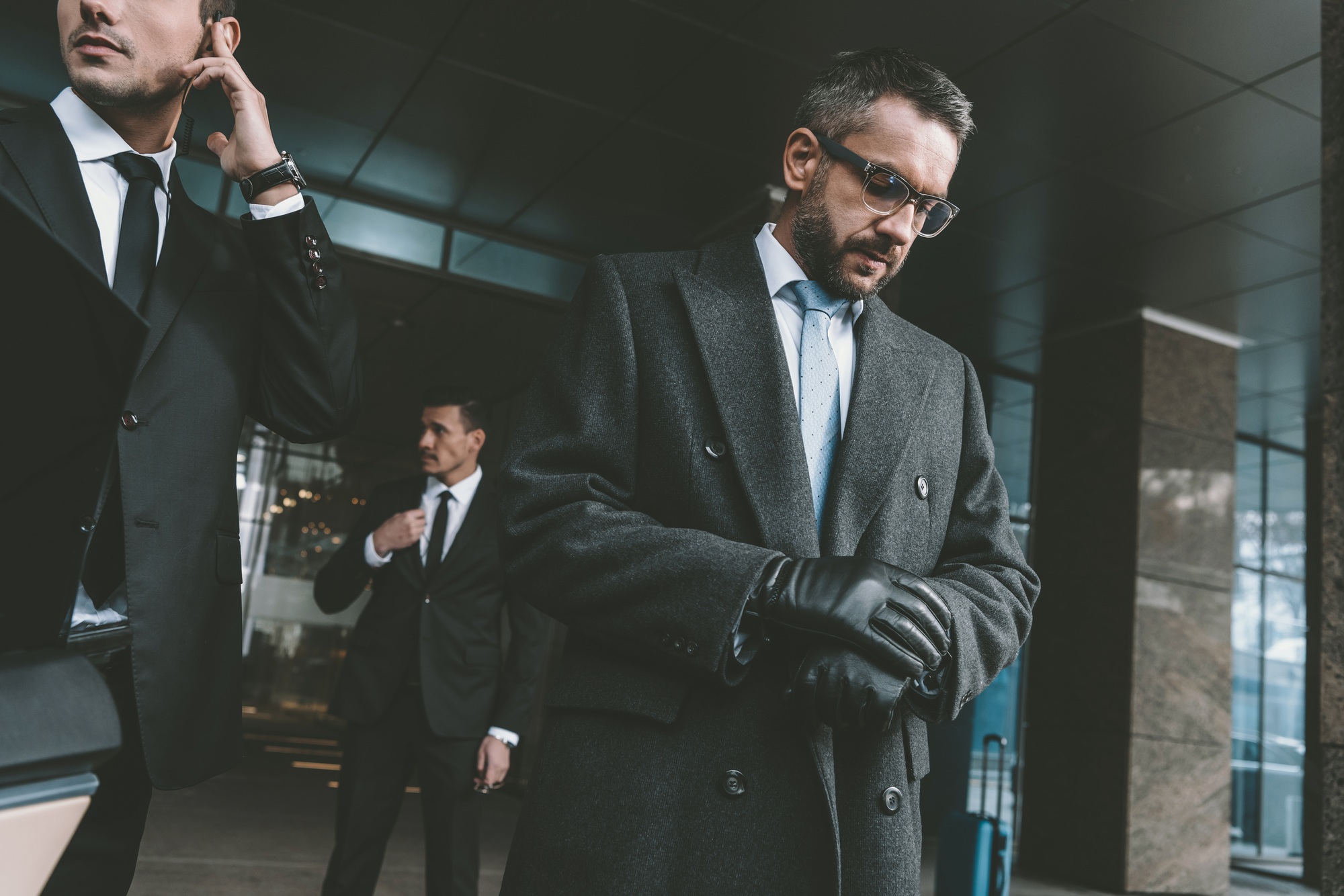 businessman looking at watch and standing with bodyguards